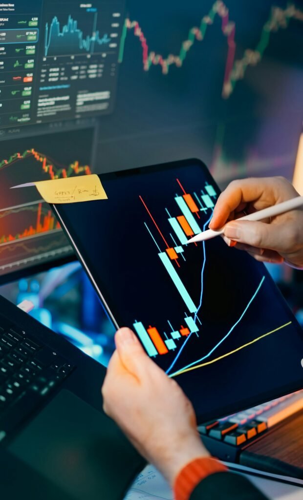 Trader analyzing crypto candlestick charts on tablet and monitor